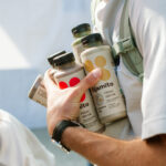 Young male holding bottles of healthy fast food.